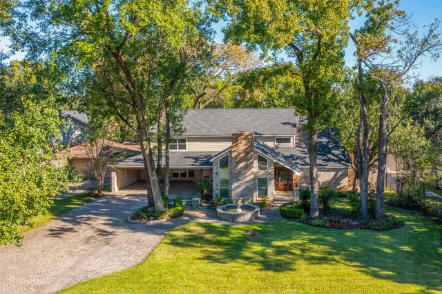 a view of a house with a big yard plants and large trees