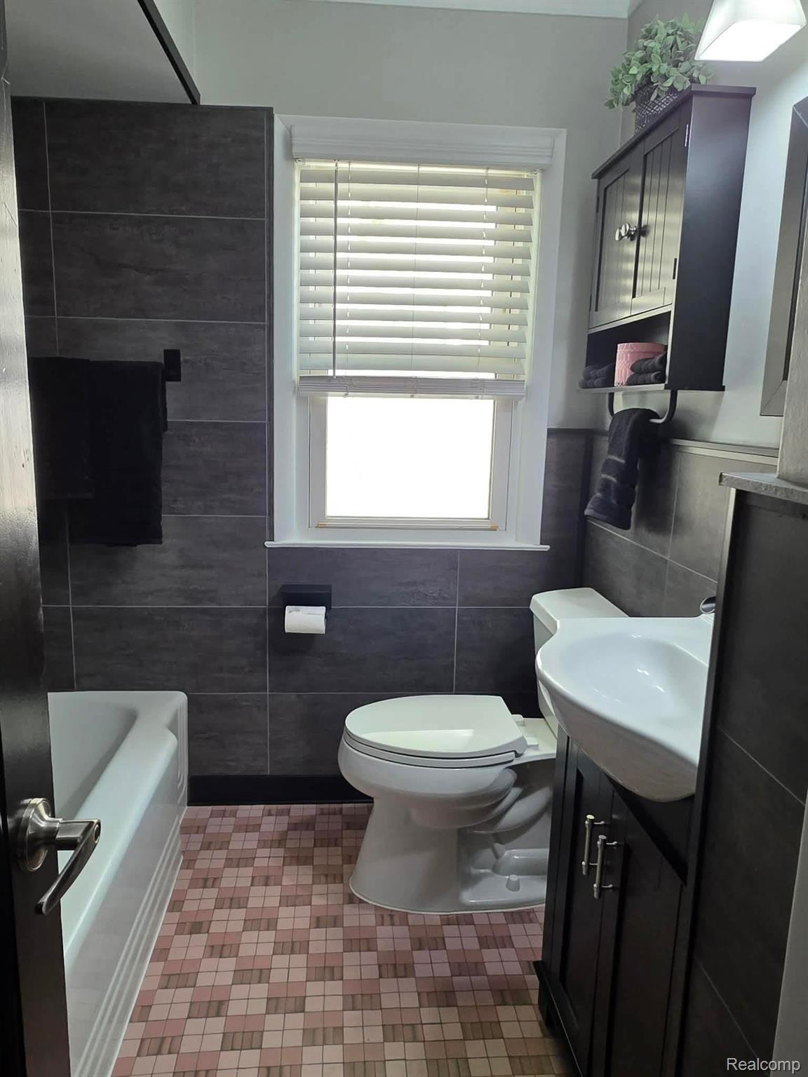 29571 Kelly Road Roseville, MI 48066 - Photo 7 of 27 Bathroom with vanity, tile walls, bathing tub / shower combination, and wainscoting