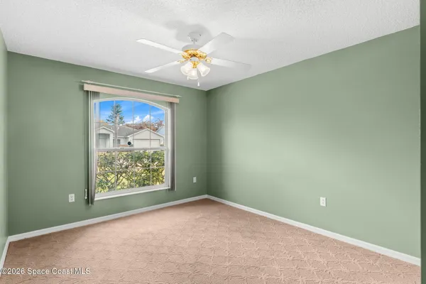 an empty room with windows and chandelier fan