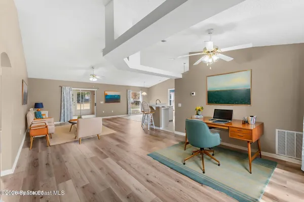 a living room with furniture a flat screen tv and kitchen view