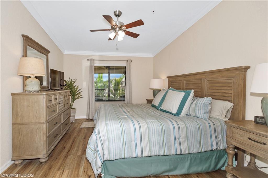 9529 Avellino Way, Unit 2823 Naples, FL 34113 - Photo 11 of 25 a bedroom with a bed and a chandelier