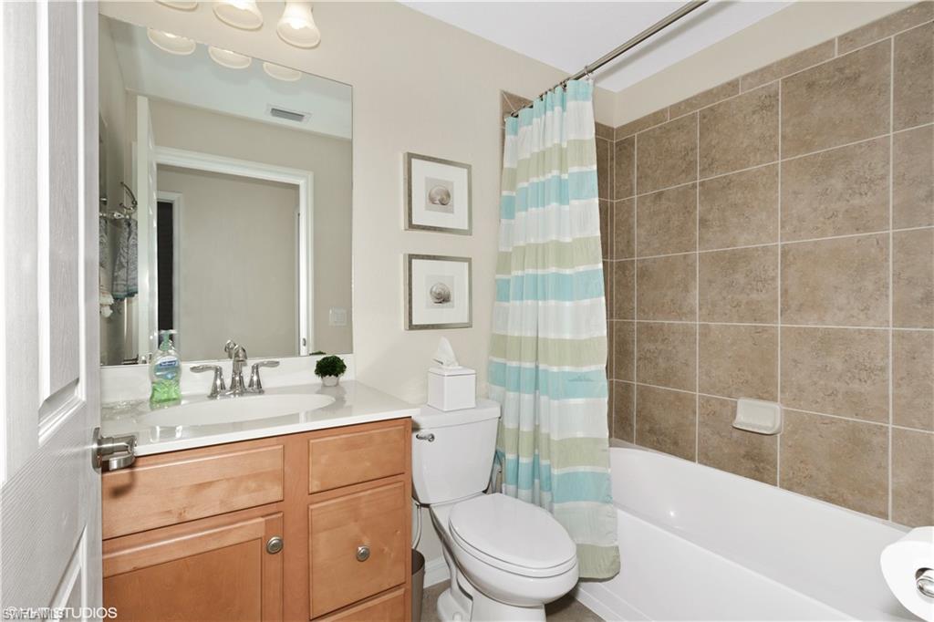 9529 Avellino Way, Unit 2823 Naples, FL 34113 - Photo 14 of 25 a bathroom with a sink a toilet a mirror a bathtub and shower