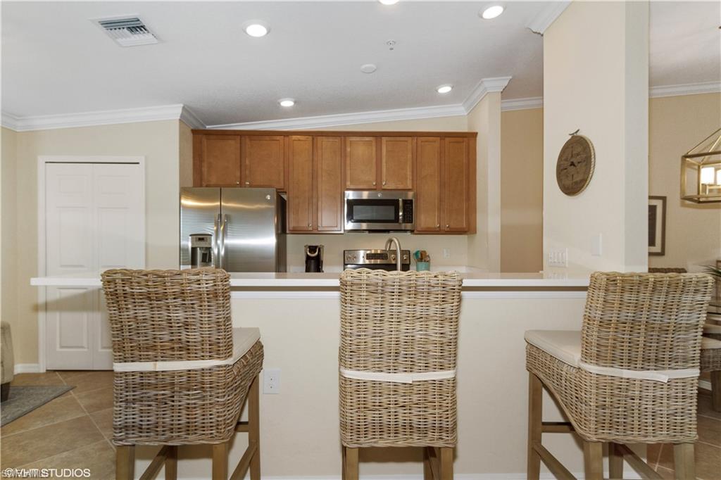 9529 Avellino Way, Unit 2823 Naples, FL 34113 - Photo 7 of 25 a kitchen with granite countertop a sink and a refrigerator