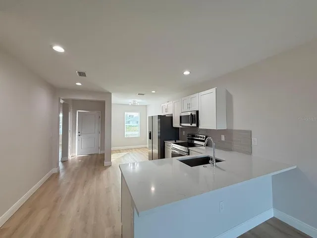 a view of kitchen with kitchen island stainless steel appliances refrigerator sink and stove
