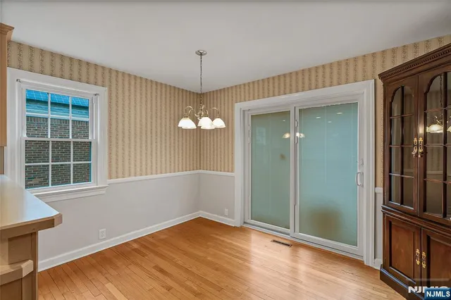an empty room with wooden floor cabinet and windows