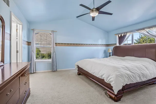 a bedroom with a large bed and a chandelier fan