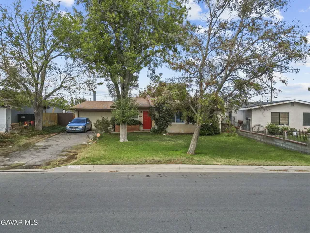 a front view of a house with a yard and large tree