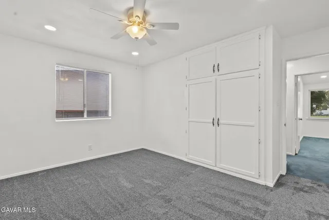 an empty room with a ceiling fan and a window