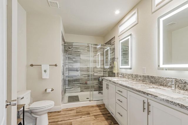 a en suite bathroom with a granite countertop sink and a shower