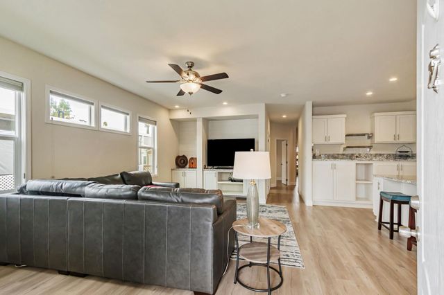 a living room with furniture kitchen view and a wooden floor