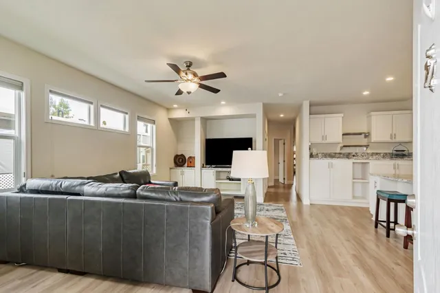 a living room with furniture kitchen view and a wooden floor