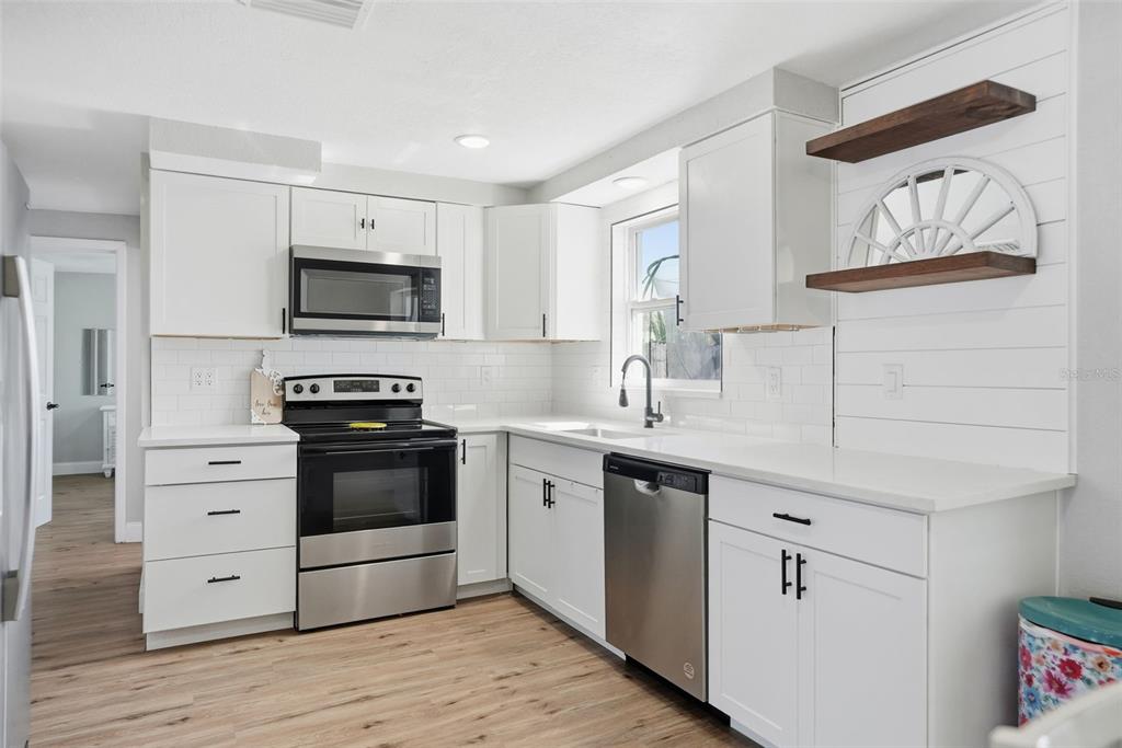 4750 Foothill Drive Holiday, FL 34690 - Photo 13 of 38 a kitchen with stainless steel appliances a stove microwave and cabinets
