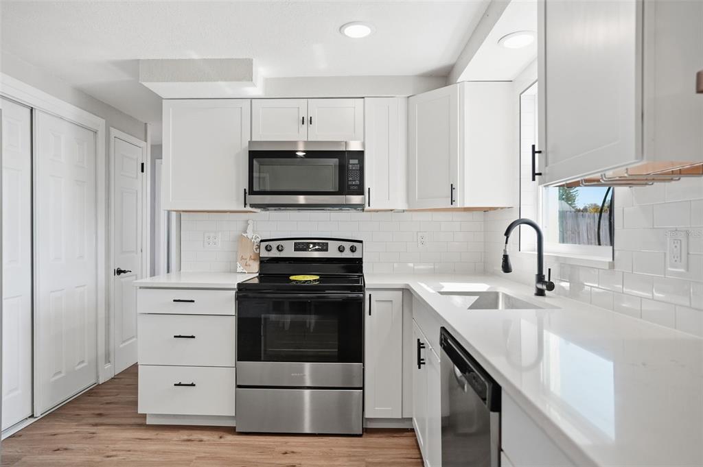 4750 Foothill Drive Holiday, FL 34690 - Photo 14 of 38 a kitchen with white cabinets and stainless steel appliances