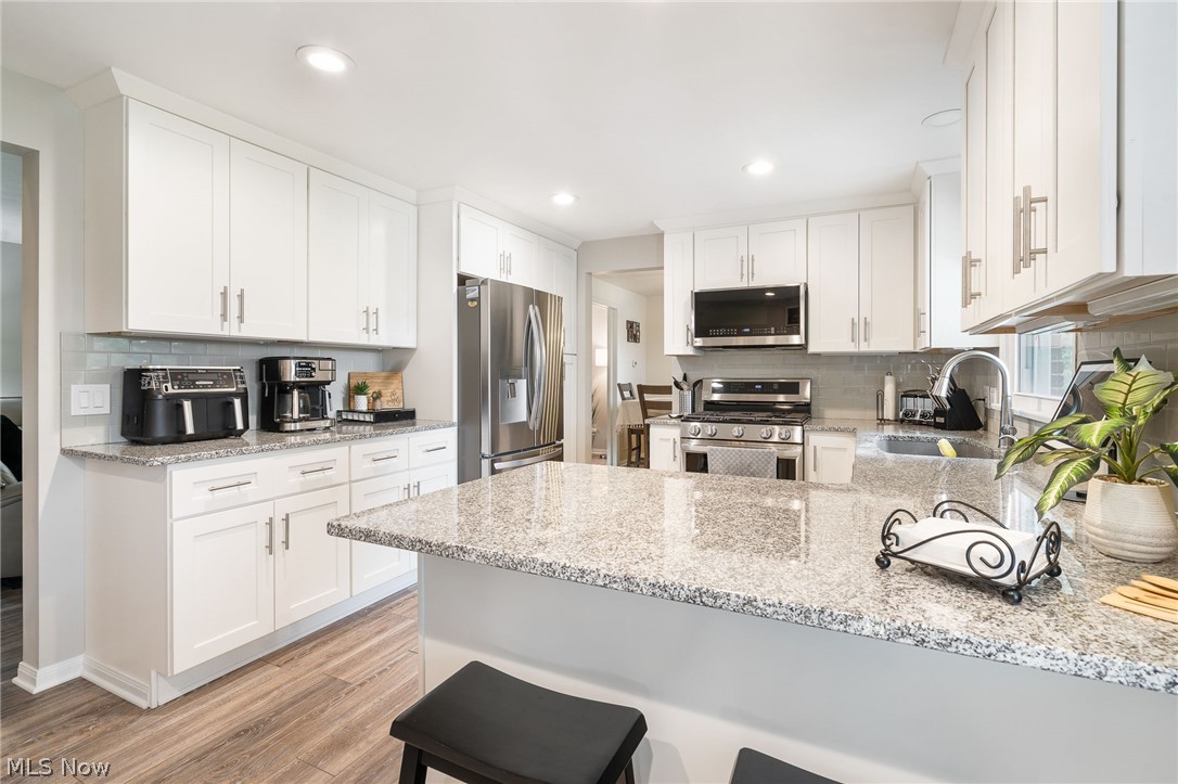 1827 Spring Valley Avenue Northwest Canton, OH 44708 - Photo 12 of 32 remodeled kitchen with all new white cabinets, quartz countertops, breakfast bar, & stainless steel appliances