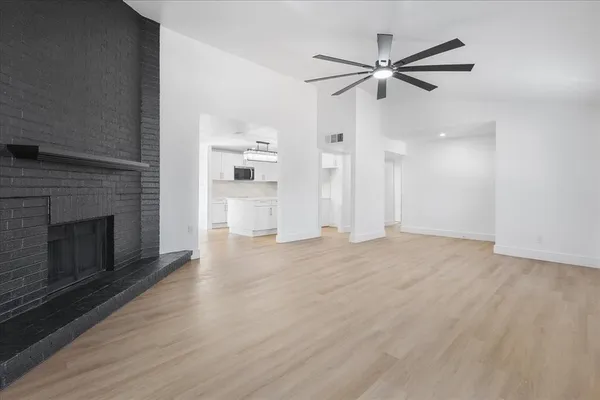 a view of a livingroom with a fireplace a ceiling fan and wooden floor