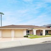 a front view of a house with a garden and mountain view