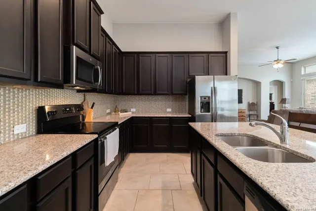 a kitchen with granite countertop a sink dishwasher stove and cabinets with wooden floor