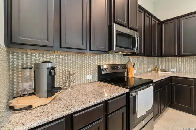a kitchen with granite countertop a sink a stove and cabinets