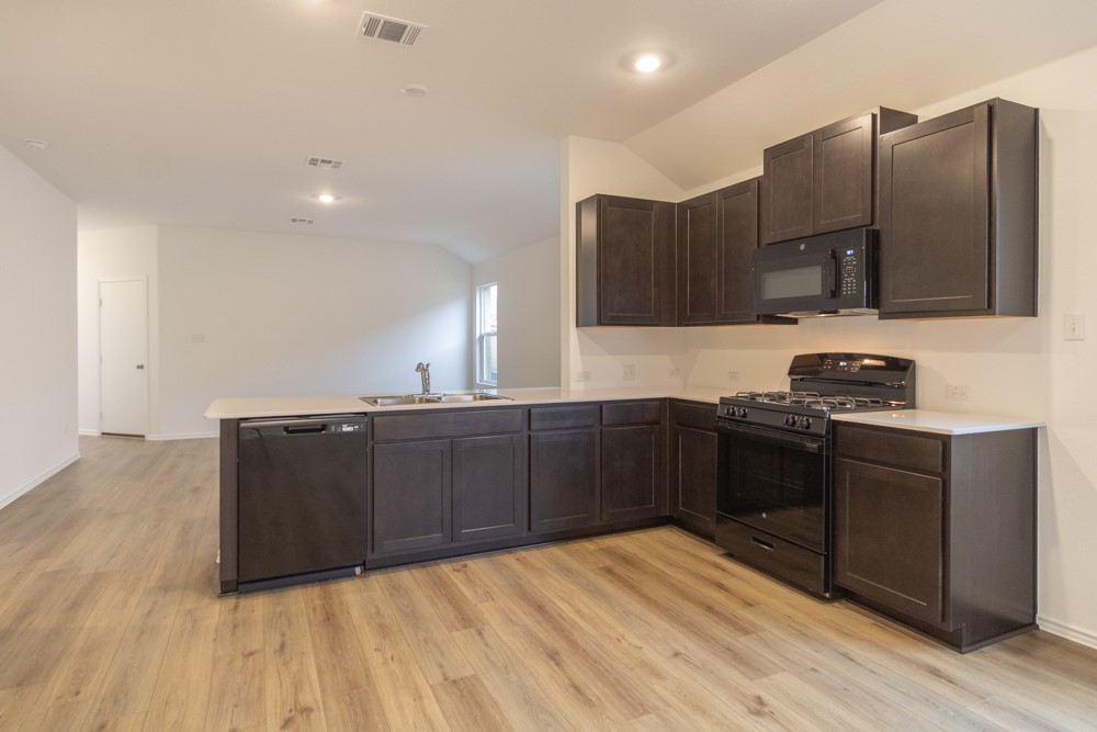 309 Canley Loop Hutto, TX 78634 - Photo 4 of 27 a kitchen with stainless steel appliances granite countertop a stove a sink and a refrigerator