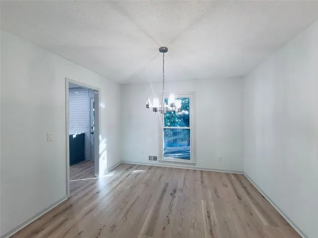 an empty room with wooden floor chandelier fan and windows