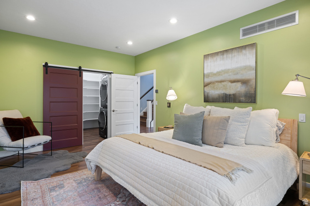 1263 Chapman Court Alpine, UT 84004 - Photo 70 of 83 Bedroom with a barn door, a spacious closet, stacked washer and clothes dryer, wood finished floors, and recessed lighting