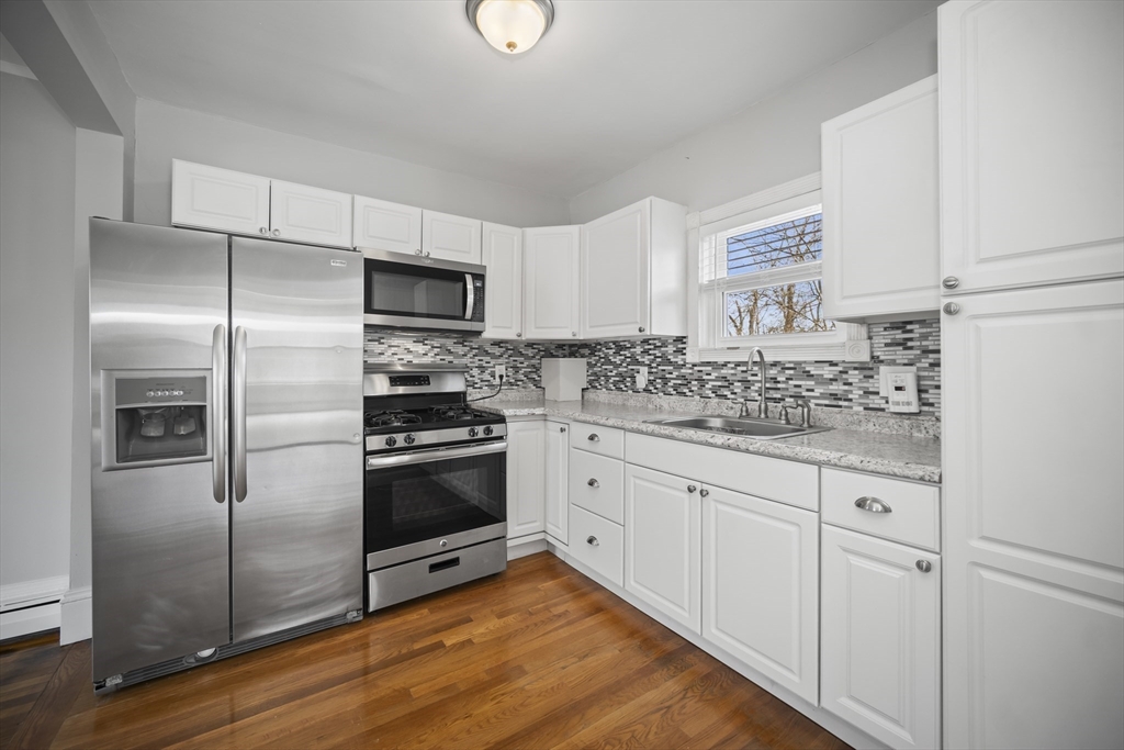 465 High Street, Unit 2 Dedham, MA 02026 - Photo 3 of 12 a kitchen with granite countertop stainless steel appliances a refrigerator stove and sink