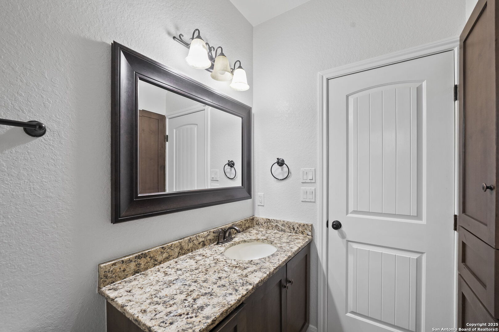 622 North Dickson Street Poth, TX 78147 - Photo 22 of 60 a bathroom with a granite countertop sink and a mirror