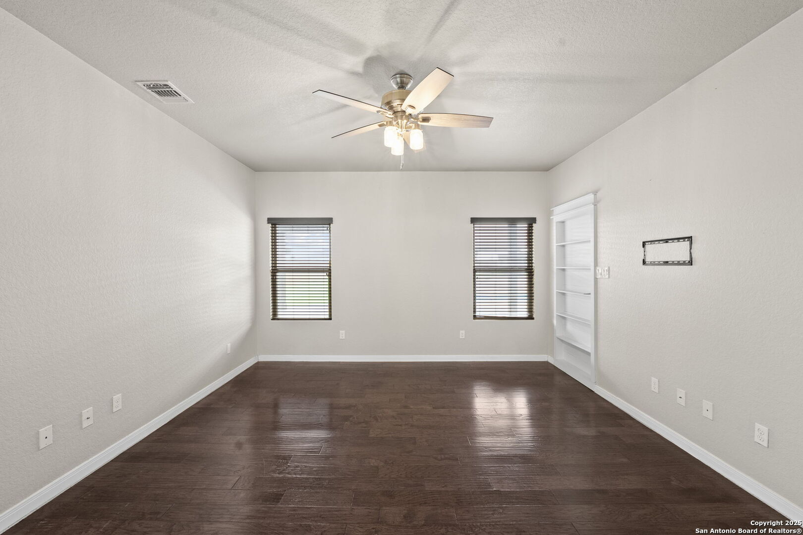 622 North Dickson Street Poth, TX 78147 - Photo 24 of 60 an empty room with wooden floor chandelier fan and windows
