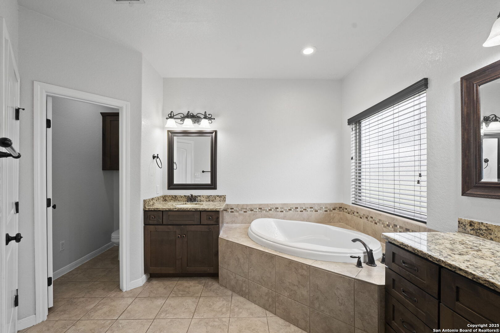 622 North Dickson Street Poth, TX 78147 - Photo 30 of 60 a bathroom with a granite countertop tub sink and mirror