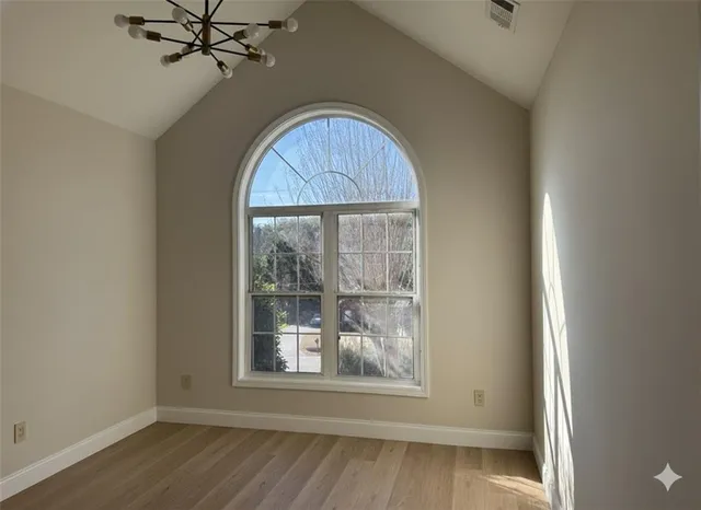 an empty room with wooden floor fan and windows