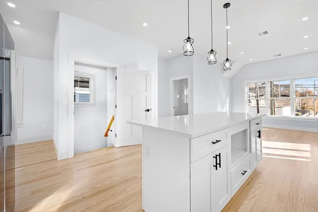 a large white kitchen with center island and a wooden floor