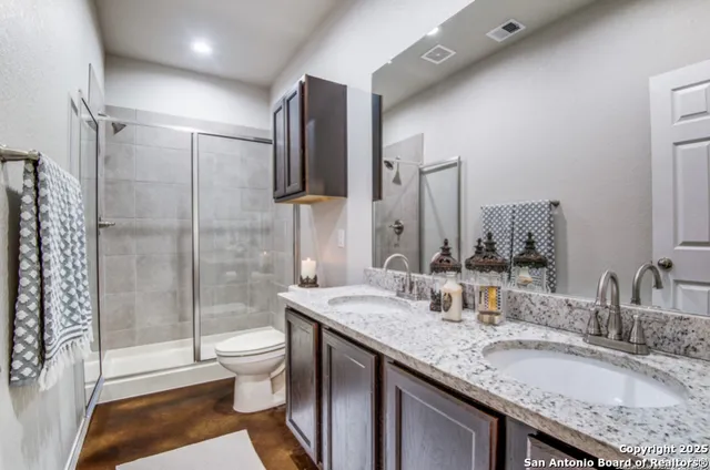 a bathroom with a granite countertop sink a toilet a mirror and shower