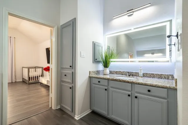 a en suite bathroom with a granite countertop sink and a mirror