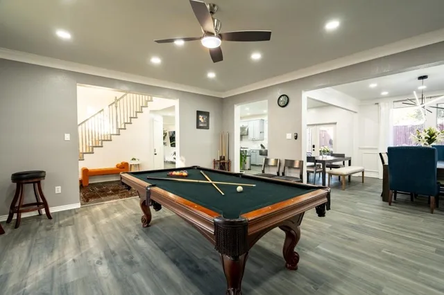 a living room with wooden floor and pool table