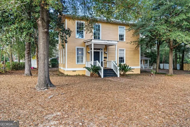 a view of a house with backyard and trees