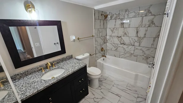 a bathroom with a granite countertop sink toilet and shower