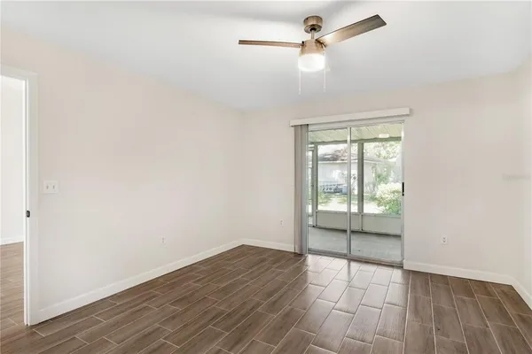 an empty room with wooden floor fan and windows