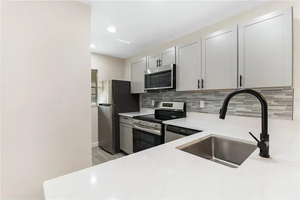 a kitchen with stainless steel appliances a stove a sink a microwave and refrigerator