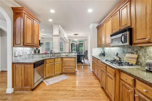 a large kitchen with stainless steel appliances granite countertop a large stove a sink and a microwave
