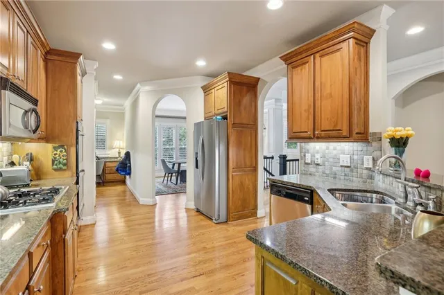 a kitchen with stainless steel appliances granite countertop a sink a stove and a wooden floors