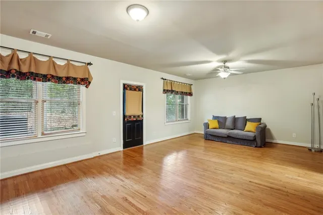 a view of an empty room with window and wooden floor