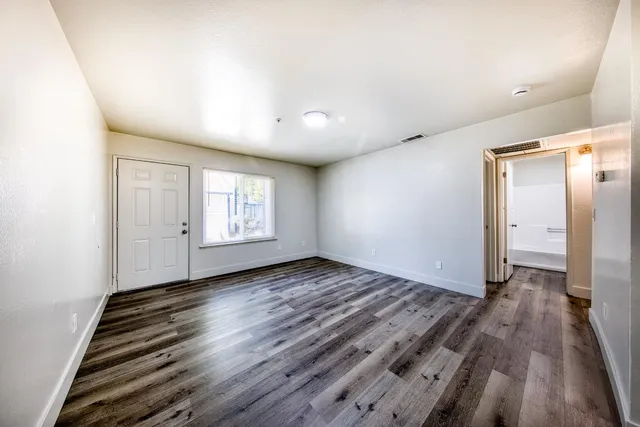 a view of an empty room with wooden floor and a window