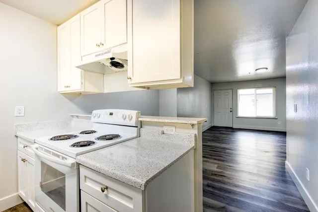 a kitchen with granite countertop a sink a stove and cabinets
