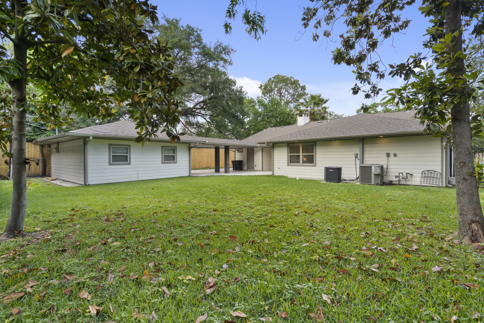 2402 Chimney Rock Road Houston, TX 77057 - Photo 34 of 36 Expansive backyard shaded by mature trees, featuring a large grassy lawn and a fully fenced layout—ideal for outdoor gatherings, play, or peaceful relaxation.