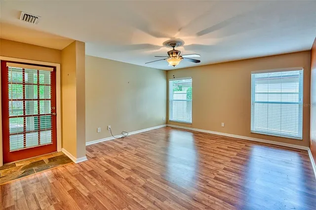 a view of an empty room with a window and wooden floor