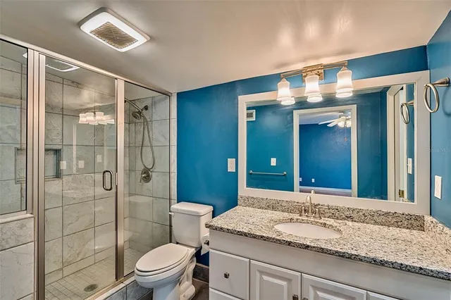 a bathroom with a granite countertop sink toilet a large mirror and shower