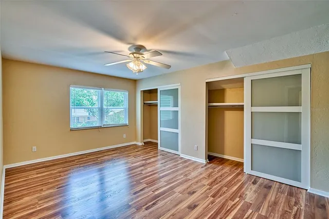 a view of an empty room with a window and wooden floor