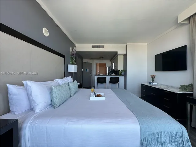 a bedroom with a large bed and a flat tv screen on dresser