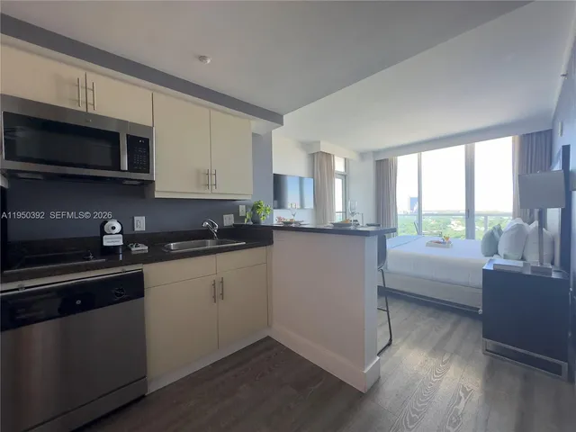 a kitchen with stainless steel appliances granite countertop a refrigerator a sink dishwasher a stove top oven a counter space and cabinets