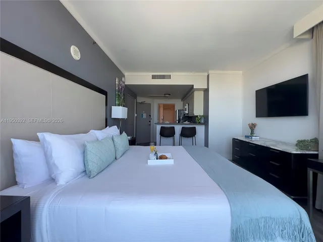 a bedroom with a large bed and a flat tv screen on dresser